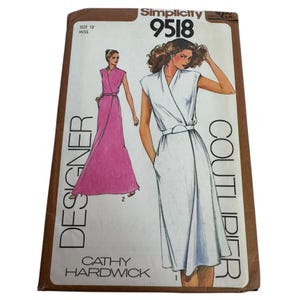 Può includere: Modello di cucito Simplicity 9518 con un abito firmato Cathy Hardwick. Il modello include illustrazioni di un abito a portafoglio bianco e rosa. La copertina riporta le parole "Designer" e "Couturier".