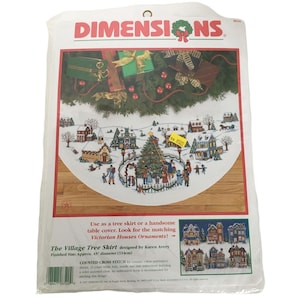 Puede incluir: Un kit de punto de cruz contado Dimensions para una falda de árbol o una cubierta de mesa. El diseño presenta una escena de pueblo invernal con un árbol de Navidad, casas y personas. El tamaño final es de aproximadamente 114 cm de diámetro.