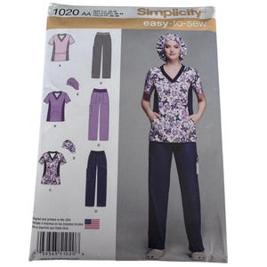 May include: Simplicity 1020 sewing pattern envelope for a V-neck scrub top, pants, and a scrub cap. The pattern features a floral print top with dark side panels, solid dark pants, and a matching floral cap, with sizing information for US 10-18.