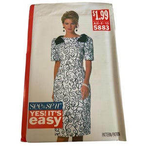 May include: A vintage sewing pattern featuring a woman in a white dress with black swirl patterns. The dress has short sleeves and black accents on the shoulders. The pattern includes the text "see & sew YES! IT'S easy" and a price tag.