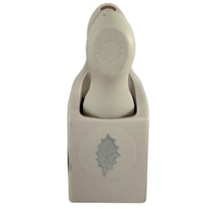 May include: A Martha Stewart cream-colored paper punch with a leaf design. The punch has a rounded handle with the words "MARTHA STEWART" printed in a circle. The leaf design is in a circle on the front of the punch.