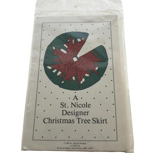 May include: A package for a Christmas tree skirt designed by St. Nicole. The design features a red starburst pattern on a green background. The text on the package reads "Christmas Tree Skirt".
