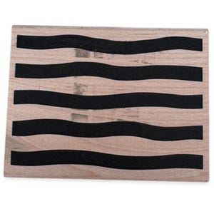 May include: A rectangular wooden block stamp featuring five horizontal black wavy lines across the light brown wood grain surface. The stamp has a flat top and a smooth finish, designed for creating repeating patterns with ink or paint.