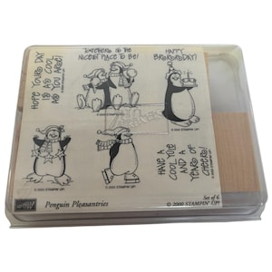 Pode incluir: Um conjunto de seis selos Penguin Pleasantries numa caixa de plástico transparente. Os selos apresentam pinguins de desenho animado em várias poses, usando chapéus e cachecóis. O texto inclui "Happy Brororoday!"