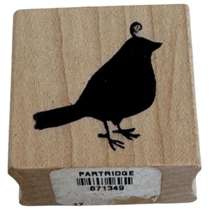 Könnte beinhalten: Ein Holzstempel mit einer schwarzen Vogelsilhouette. Der Vogel hat eine dekorative Locke auf dem Kopf. Das Wort "PARTRIDGE" ist auf einem Etikett am unteren Rand des Stempels zusammen mit der Nummer "871349" aufgedruckt.