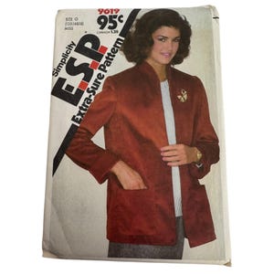 May include: A vintage Simplicity Extra-Sure Pattern envelope featuring a woman wearing a rust-colored jacket with pockets and a gold brooch. The envelope has text including "Simplicity ESP" and "Extra-Sure Pattern". The price is marked as 95¢.