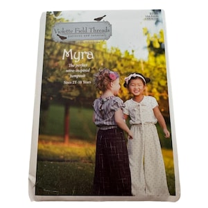 May include: A sewing pattern for a jumpsuit called "Myra" by Violette Field Threads. The pattern is for sizes 2T-10 years and features a retro-inspired design. The pattern cover shows two young girls wearing the jumpsuit in a park setting.