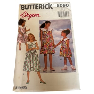 May include: Butterick 6090 sewing pattern for girls' dresses. The pattern shows dresses with floral and striped designs, white collars, and tie details. The cover has the name "Bryan" in red script.