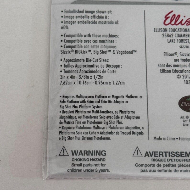 Op de afbeelding: Een wit productverpakkingslabel met zwarte tekst die de compatibiliteit met Sizzix BIGkick, Big Shot en Vagabond machines beschrijft. Het vermeldt stansmaten van 7,62 cm x 10,16 cm en 0,95 cm x 1,27 cm, platformvereisten en een waarschuwing voor verstikkingsgevaar.