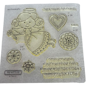 May include: Clear acrylic stamps with angel, heart, and floral designs. Text includes "Thank heaven for friends" and a quote about friendship. The stamps vary in size, with the angel measuring approximately 1.9 cm.