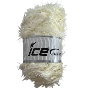 Könnte beinhalten: Ein Knäuel cremefarbener, flauschiger Wolle. Die Wolle hat ein strukturiertes, flauschiges Aussehen. Das Etikett trägt die Aufschrift "ice yarns" mit einem Sternlogo. Dieses Garn eignet sich für Strick- und Häkelprojekte.