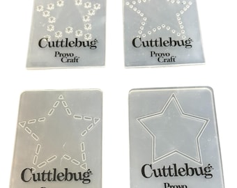 May include: Four clear plastic Cuttlebug Provo Craft stencils with star designs. Each stencil has a different star pattern: floral, dotted, geometric, and outlined. The Cuttlebug and Provo Craft logos are printed in black.