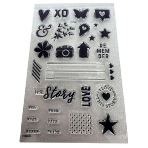 May include: Clear acrylic stamps with various designs, including hearts, a butterfly, a camera, and the words "The Story" and "Love This Story." The set also includes stamps for "Who," "When," "What," "Date," "Where," and "Place."