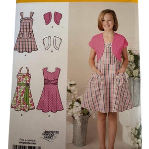 May include: Simplicity sewing pattern 1927A featuring a girl's dress and bolero. The pattern includes multiple dress designs, including a plaid dress with pockets. Sizes available are U.S. 7, 8, 10, 12, 14, and 16. The pattern is from the American Sewing Guild.