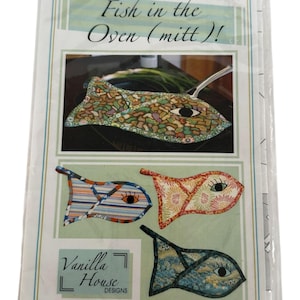 May include: A package featuring a fish-shaped oven mitt and three fish-shaped potholders. The mitt and potholders have decorative patterns and eye details. The text "Fish in the Oven (mitt) !" is at the top, with "Vanilla House Designs" at the bottom.