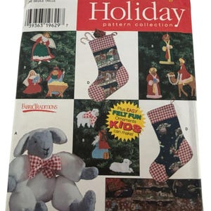 Könnte beinhalten: Simplicity Holiday Schnittmusterkollektion mit Filzornamenten und Weihnachtsstrümpfen. Das Muster enthält Anleitungen zur Herstellung von Filzornamenten und Strümpfen mit verschiedenen Designs, darunter Engel, Krippenszenen und ein Plüschlamm.