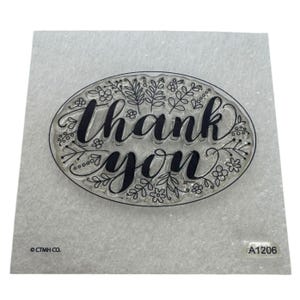 Op de afbeelding: Transparante stempel met de woorden "thank you" in sierlijk schrift, omringd door bloemen- en bladerontwerpen. De ovale stempel ligt op een lichtgrijze achtergrond. De stempel heeft de tekst "CTMH CO." en "A1206".