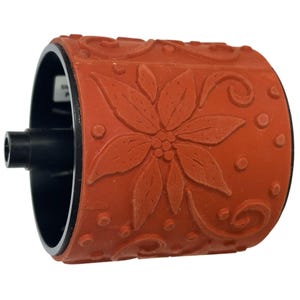 May include: A red rubber stamp with a poinsettia flower design and decorative swirls. The stamp has a black handle and a black roller. The stamp is designed for crafts and scrapbooking.
