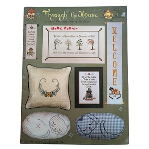 May include: A vintage craft pattern book titled "Through the House." The cover features cross-stitch designs, including a pillow with floral embroidery, sleeping cat pillows, and a "Welcome" banner. The book includes the text "Belle Collier."