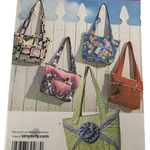 May include: Simplicity pattern 3822 featuring five tote bag designs. The bags vary in color and pattern, including floral, patchwork, and polka dots. Each bag has a different handle style and decorative elements. The pattern includes the text "ONE SIZE".