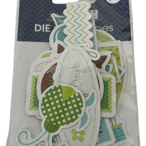 Pode incluir: Um pacote de 37 enfeites de papel recortados em várias formas e desenhos. Os autocolantes apresentam uma paleta de cores verde, azul, castanho e branco. Alguns autocolantes têm a palavra "Day!" impressa.