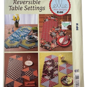 May include: A sewing pattern titled "Reversible Table Settings" by ellie mae designs. The cover features four different table setting designs with various patterns and colors, including floral, plaid, and geometric shapes. The pattern number is K186.