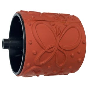 May include: A red rubber stamp with a butterfly design. The stamp has a cylindrical shape with a black interior and a black handle. The butterfly design is raised and detailed, with small circular accents.