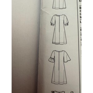May include: A black and white sewing pattern illustration showing technical line drawings of three different dress designs. The sketches feature various sleeve lengths, including puffed sleeves with cuffs and flared sleeves, all presented on a white paper background.