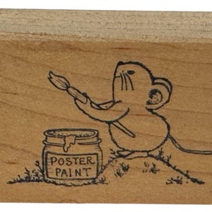 Może przedstawiać: Drewniana pieczątka przedstawiająca mysz z kreskówki trzymającą pędzel, gotową do pomalowania słoika farby plakatowej. Na słoiku napis "POSTER PAINT". Pieczątka wykonana jest z jasnego drewna.