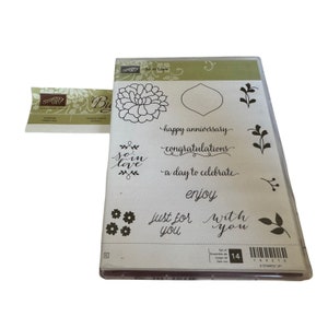 May include: A set of 14 clear stamps with a floral design, a heart, and various phrases including "so in love", "happy anniversary", "congratulations", "a day to celebrate", "enjoy", "just for you", and "with you".