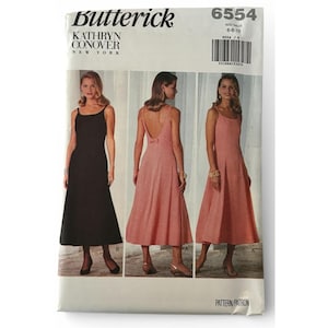 May include: Butterick 6554 Kathryn Conover sewing pattern envelope for a sleeveless dress with a square neckline and a low back. The pattern features two variations: a black dress and a pink dress with a small bow detail at the back waist.