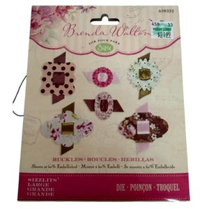 May include: A pack of Sizzix die-cut buckles in various floral and patterned designs. The package features six different buckle shapes in shades of pink, brown, and white. The package has the text "Brenda Walton" and "Buckles" printed on it.