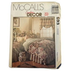 May include: A McCall's Creative Decor sewing pattern envelope, number 693, featuring an illustration of a bedroom with a floral print bedspread, a ruffled bed skirt, and a window valance. The package includes a barcode and text labels.