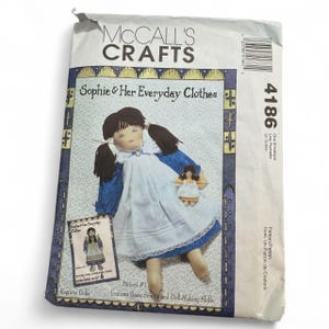 May include: A McCall's Crafts sewing pattern envelope titled "Sophie & Her Everyday Clothes." The pattern features a rag doll wearing a blue dress and white apron. The envelope includes the number 4186 and text that reads "Features Basic Sewing and Doll-Making Skills."