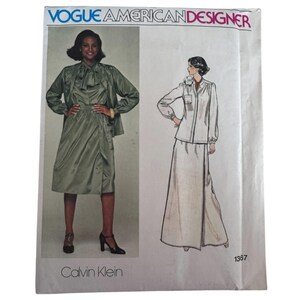 May include: Vogue American Designer sewing pattern 1367 by Calvin Klein. The envelope features a photograph of a sage green blouse and wrap skirt set, alongside a line drawing of a long-sleeved button-down shirt and a floor-length skirt.