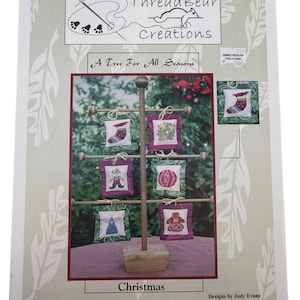 Puede incluir: Un patrón impreso para adornos de árbol de Navidad. La imagen presenta un árbol de madera con pequeños adornos cuadrados que representan diseños festivos como un calcetín, un ángel y un hombre de jengibre. El texto dice "Thread Bear Creations" y "A Tree For All Seasons".