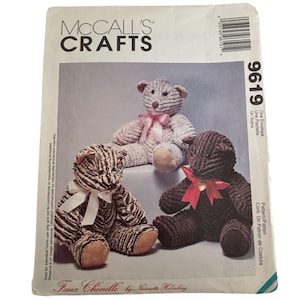 May include: A McCall's Crafts 9619 sewing pattern envelope featuring three teddy bears made of faux chenille fabric. The bears are shown in light gray, striped brown and white, and dark brown, each adorned with a decorative ribbon around the neck.