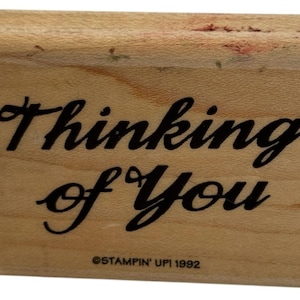 May include: A wooden stamp with the words "Thinking of You" in black cursive script. The stamp is rectangular with a curved top edge. The text "STAMPIN' UPI 1992" is printed at the bottom.