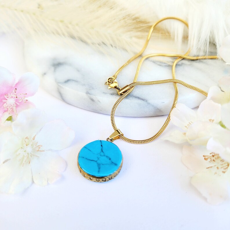Peut inclure: Un collier en cha&icirc;ne dor&eacute;e avec un pendentif rond en turquoise. Le pendentif a une bordure dor&eacute;e et une pierre turquoise marbr&eacute;e.