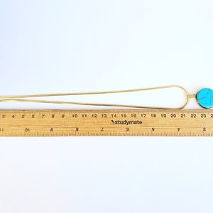 Peut inclure: Un collier en cha&icirc;ne dor&eacute;e avec un pendentif turquoise. Le pendentif est un disque rond et plat avec un motif marbr&eacute; bleu clair et blanc.