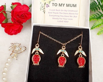 Può includere: Una scatola regalo bianca con un set di collana e orecchini a forma di melograno rosso e dorato. La scatola contiene un messaggio all'interno che dice: "Alla mia mamma, ripenso alla mia infanzia e ringrazio le stelle del cielo per tutto quello che mi hai dato, ma soprattutto per il tuo amore. Ti amo!"