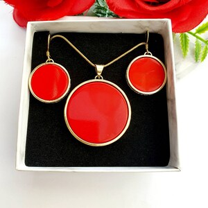 May include: A gold necklace and earrings set with red round stones. The necklace has a pendant with a larger red stone.