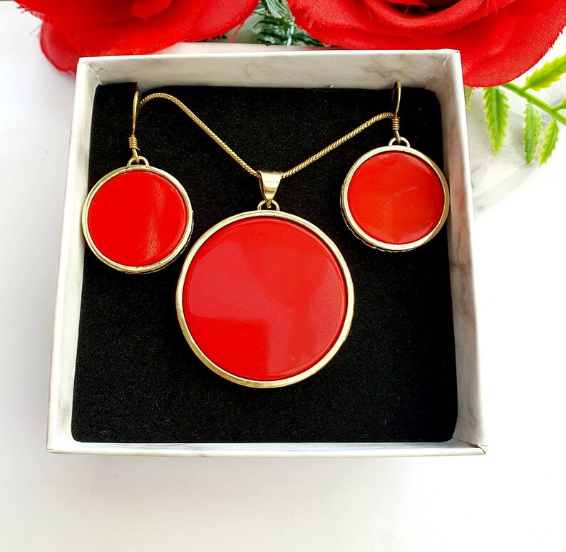 May include: A gold necklace and earrings set with red round stones. The necklace has a pendant with a larger red stone.