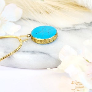 Peut inclure: Un collier en cha&icirc;ne dor&eacute;e avec un pendentif en pierre turquoise. Le pendentif est rond et a une bordure dor&eacute;e.