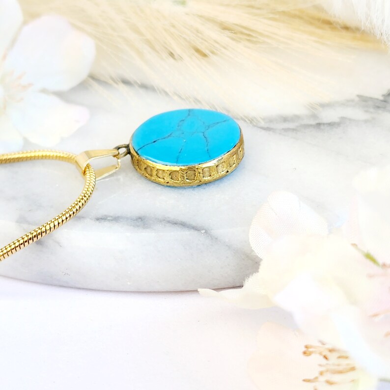 Peut inclure: Un collier en cha&icirc;ne dor&eacute;e avec un pendentif en pierre turquoise. Le pendentif est rond et a une bordure dor&eacute;e.
