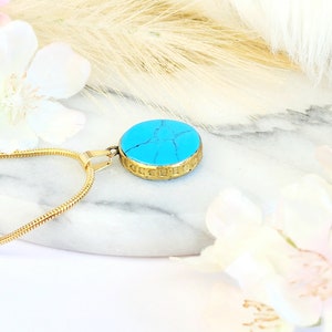 Peut inclure: Un collier en cha&icirc;ne dor&eacute;e avec un pendentif turquoise. Le pendentif est rond et a une bordure dor&eacute;e.