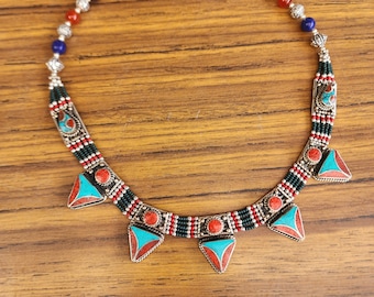 May include: A silver necklace with turquoise and red stones. The necklace has a beaded design and five triangular pendants.