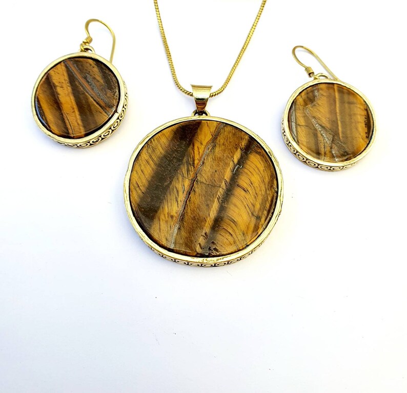 May include: A gold necklace and earrings set with round tiger's eye stone pendants.