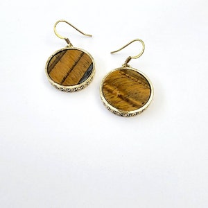 May include: A pair of gold tone earrings with round tiger's eye stone accents.