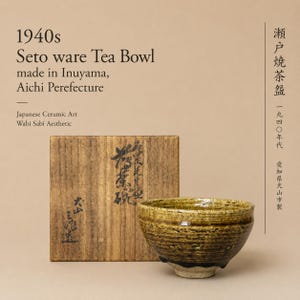 May include: A 1940s Seto ware tea bowl with a mottled brown and yellow glazed finish, accompanied by a square wooden storage box featuring black Japanese calligraphy. The text on the image reads 1940s Seto ware Tea Bowl made in Inuyama, Aichi Prefecture.